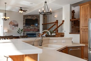 Eine moderne Küche mit Kochinsel, Edelstahlgeräten und einer Holztreppe.