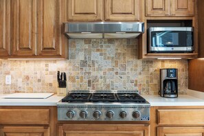 A kitchen with a gas stove, a microwave, and a coffee maker. - Sunrise Shores Estate - 4bd-4ba Luxury Lakefront (Camdenton)