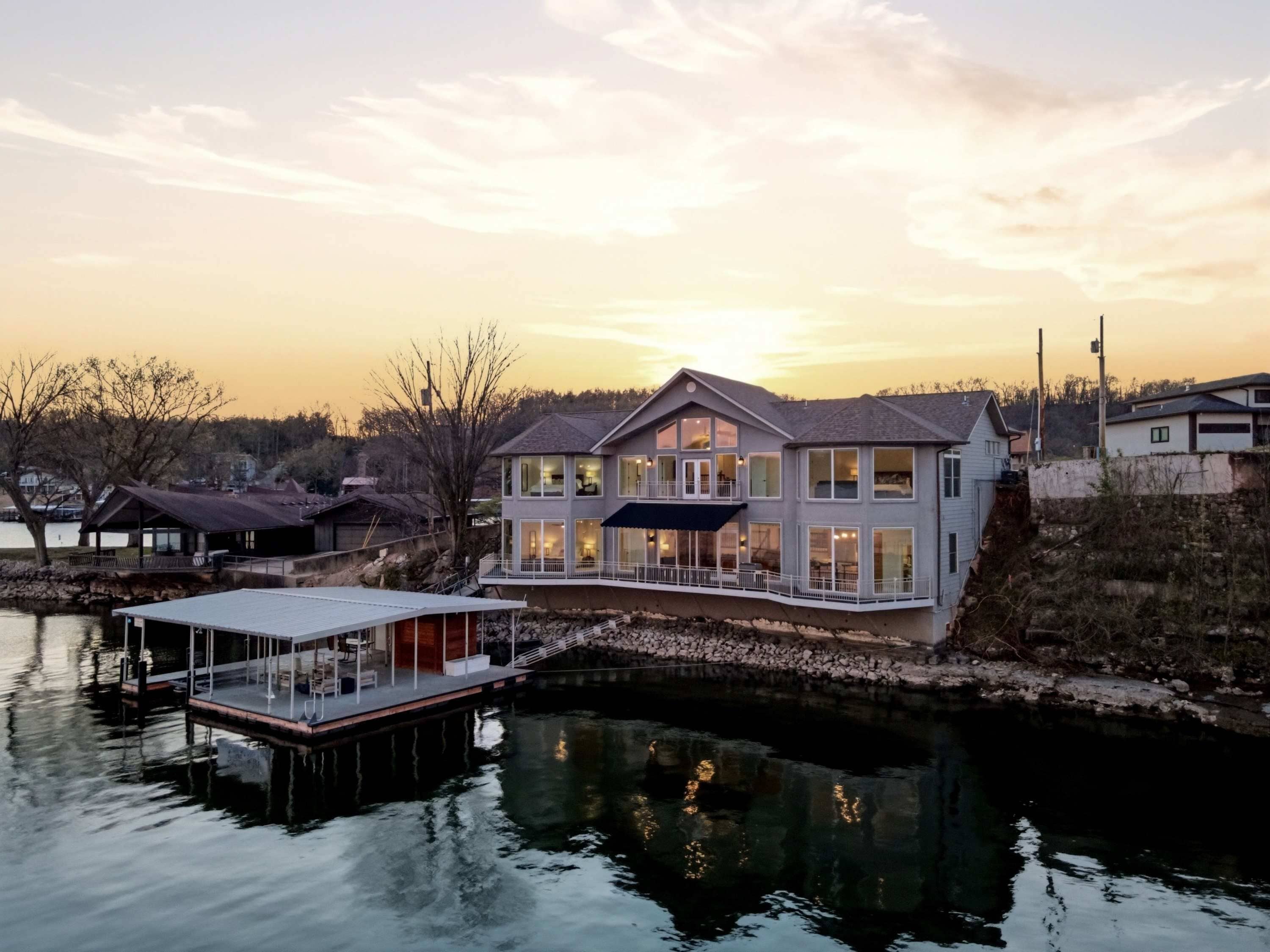 Une propriété située au bord de l’eau, comprenant une grande maison, un quai et un petit bateau.