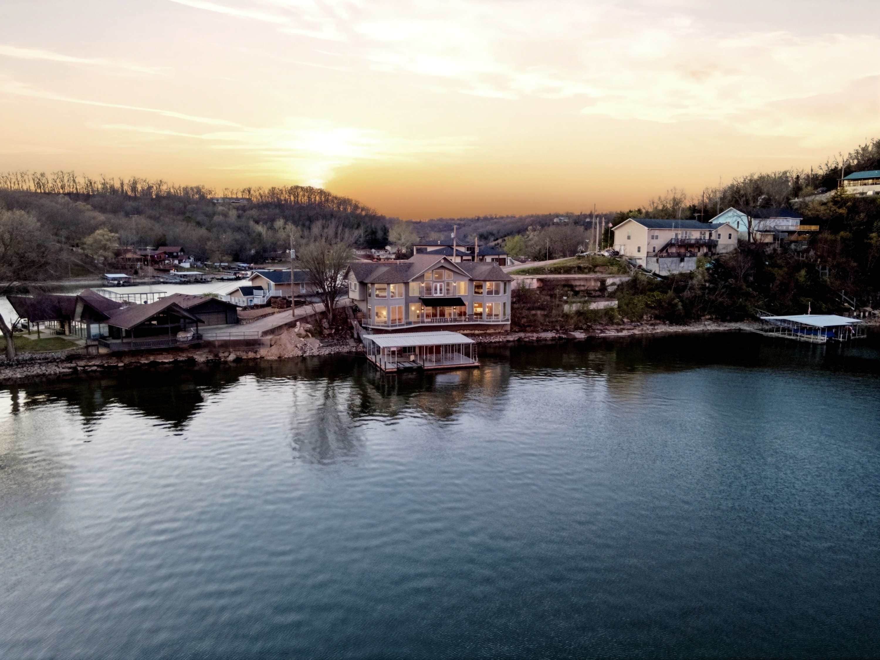 A lakeside property with a large house, dock, and surrounding buildings.