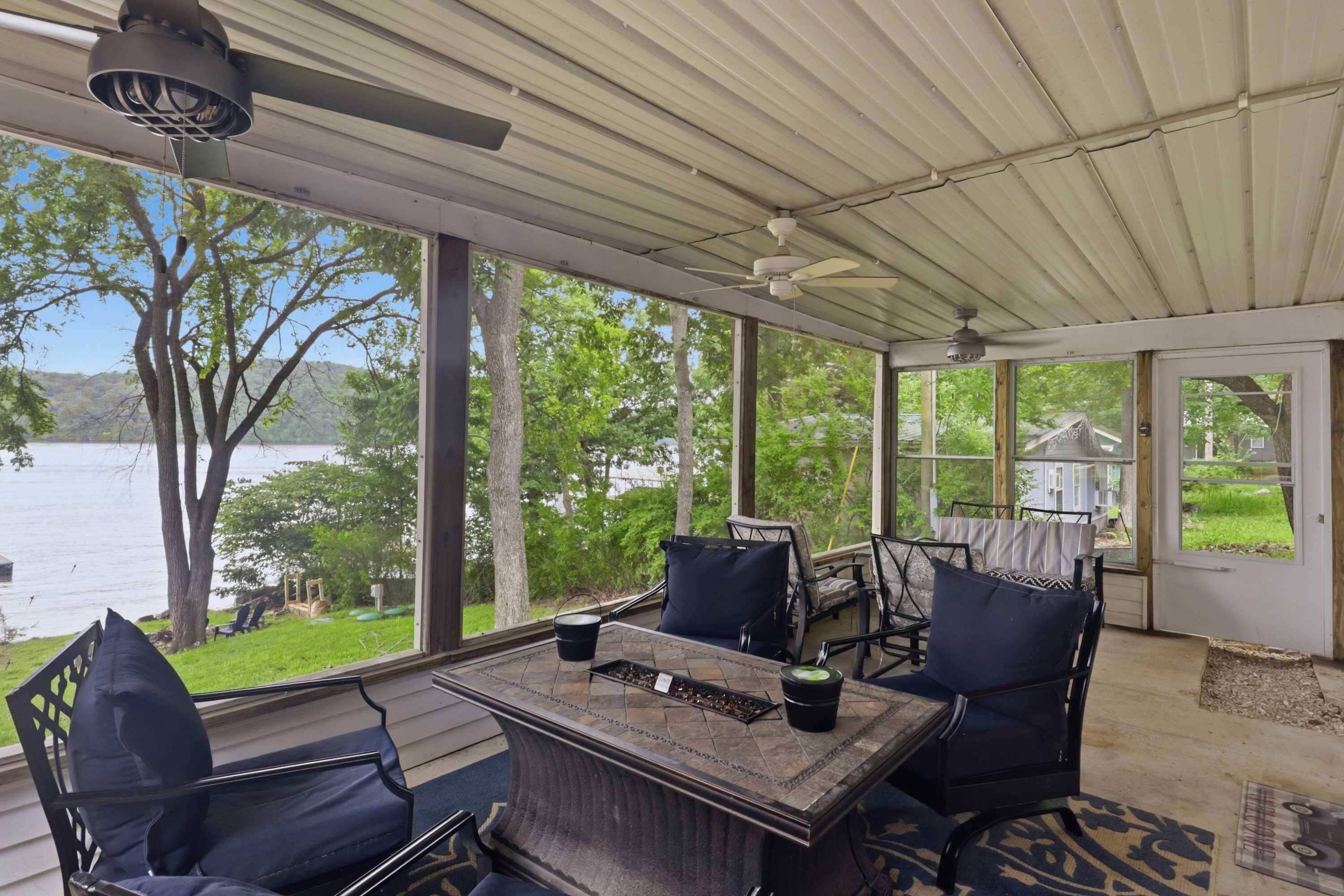 Une terrasse couverte avec une table, des chaises et une vue sur un lac.
