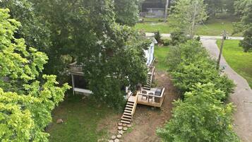 A residential area with a wooden deck, a small outdoor seating area, and a pathway leading to a house.