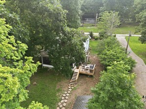 A residential area with a wooden deck, a small outdoor seating area, and a pathway leading to a house. - Visit This 4 Bedroom - 3 Bath Lakefront Home With Private Dock (Stover)