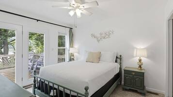 A bedroom with a bed, a nightstand, a ceiling fan, a window, and a door leading to an outdoor area.