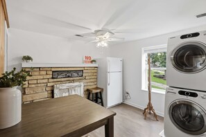 A laundry room with stacked washers and dryers, a ceiling fan, a refrigerator, and a window with a view of greenery. - Visit This 4 Bedroom - 3 Bath Lakefront Home With Private Dock (Stover)