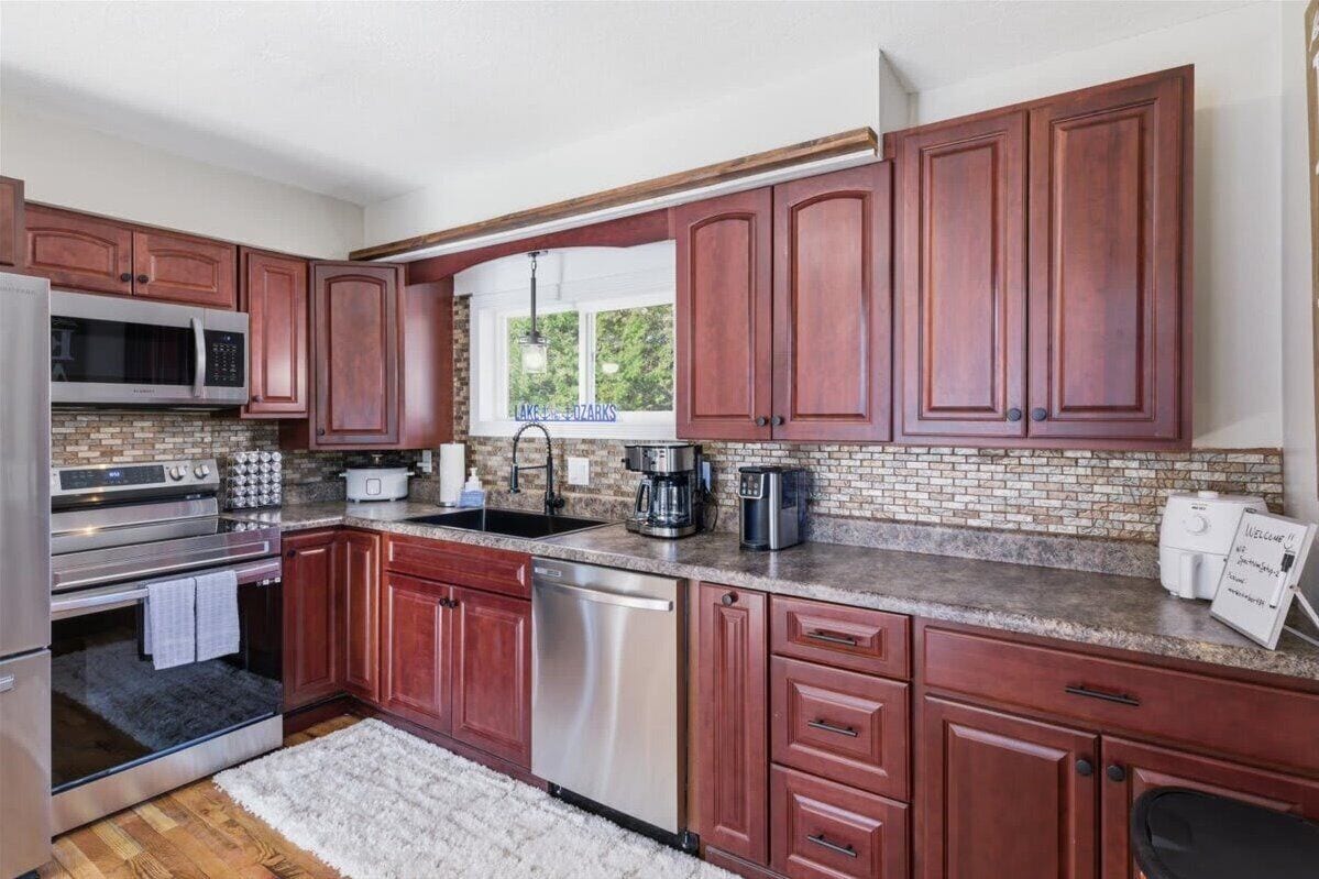 A kitchen with wooden cabinets, a stainless steel refrigerator, a microwave, a stove, a dishwasher, and a coffee maker.
