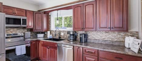 A kitchen with wooden cabinets, a stainless steel refrigerator, a microwave, a stove, a dishwasher, and a coffee maker.
