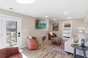 Ein Wohnzimmer mit einer Couch, einem Sessel, einem Couchtisch und einem Fernseher an der Wand.