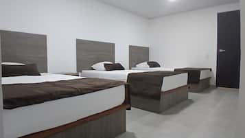 Een hotelkamer met drie bedden, elk voorzien van hoofdeind en kussens.