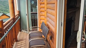 Una terraza de madera con un banco y un ventanal corredero que da a un espacio interior.