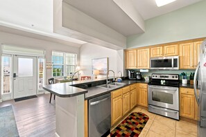 Cocina moderna con electrodomésticos de acero inoxidable, armarios de madera y una isla grande con pileta.