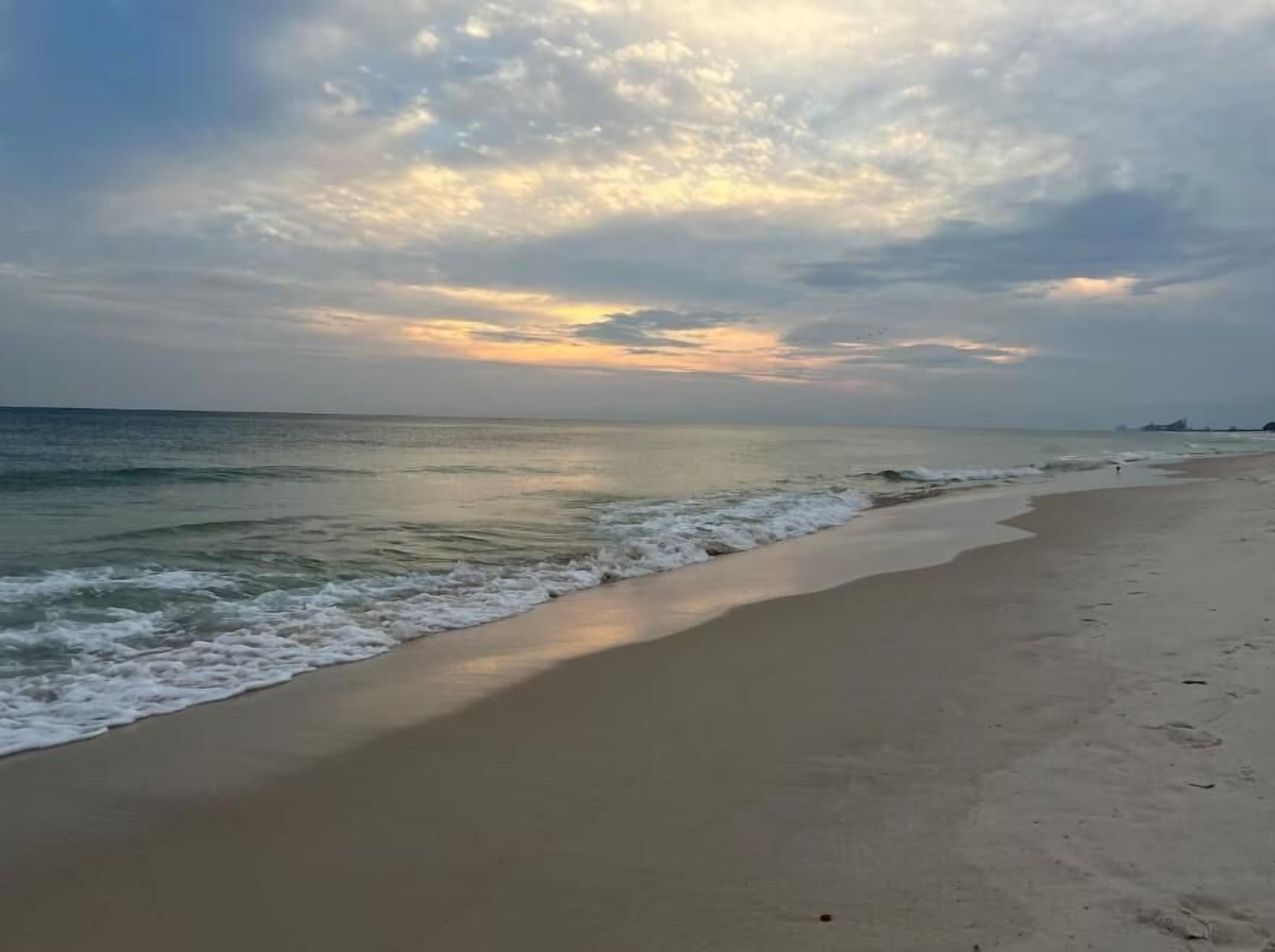A beach with a wide sandy shore and gentle waves.