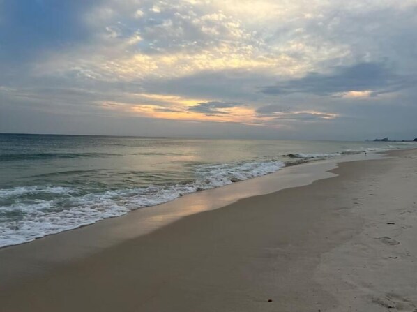 Una playa con una extensa orilla arenosa y olas suaves.