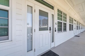 A long corridor with white doors and windows, each with a number plate. - Villagio C241 (Pensacola)