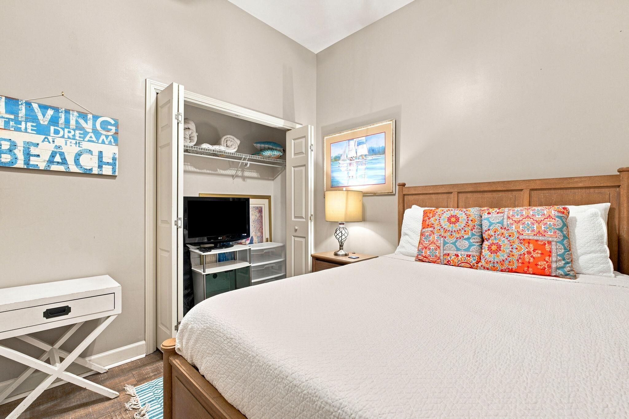 A bedroom with a bed, a TV, a desk, and a wardrobe.