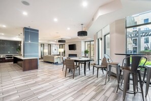 A modern kitchen with a central island, a dining area with round table and chairs, and large windows offering views of the outside. - Downtown Houston 1BR • Balcony • Fast Wi-Fi • Free In-Unit Laundry (Houston)