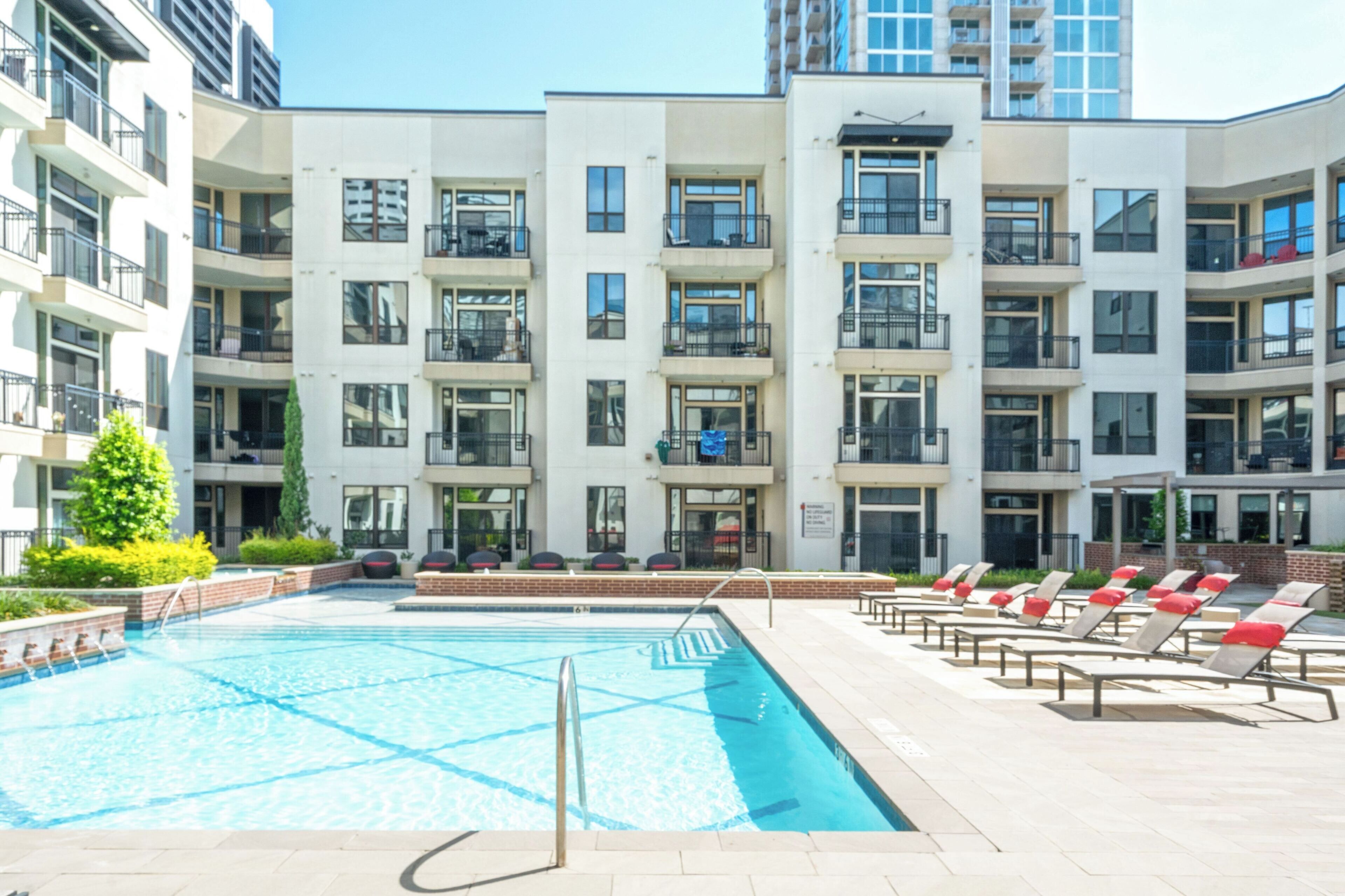 Ein modernes Apartmenthaus mit Schwimmbad und Liegestühlen.