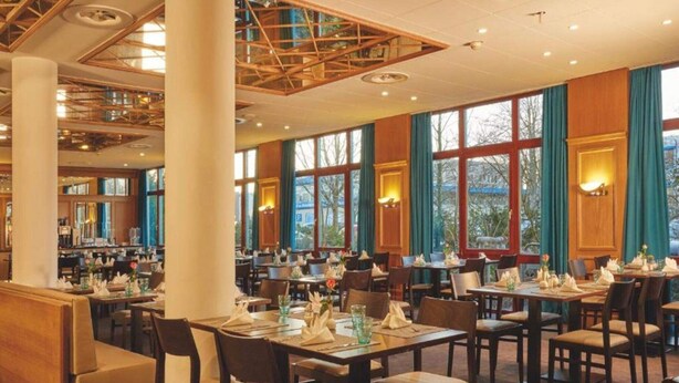 A spacious restaurant with multiple dining tables and chairs, large windows, and a high ceiling with exposed beams. - 2 Person Holiday Park Home in Hannover (Hannover)