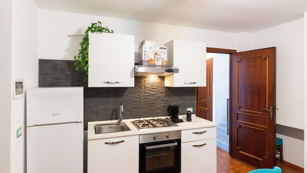 A compact kitchen with white cabinets, a built-in oven, a gas stove, and a black countertop.