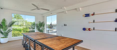 Una habitación moderna con una mesa de madera, ventiladores de techo y plantas en macetas.