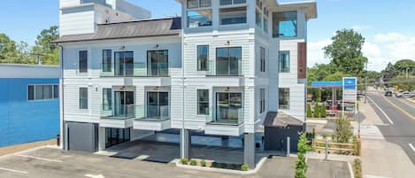 A multi-story hotel with a modern design, featuring balconies, large windows, and a parking lot.