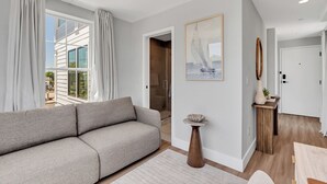 A modern living room with a grey sofa, a wooden coffee table, and a painting on the wall. - Station 1 Hotel #3 (Stonington)