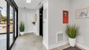 A hotel lobby with a reception desk, potted plants, a framed map, and a fire safety sign. - Station 1 Hotel #3 (Stonington)