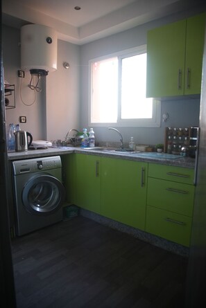 Eine kleine Küche mit Waschmaschine, Fenster und Spüle.