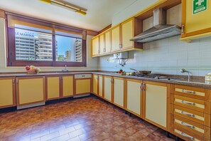 A kitchen with wooden cabinets, a window with a view of a building, and a sink. - Apartamento Vintage | 4 bedrooms | Vilamoura Marina (Vilamoura)