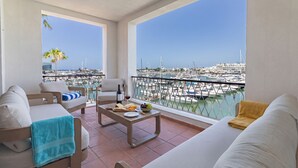 A balcony with a view of a marina, a sofa, a coffee table with food and drinks, and a chair. - Apartamento Vintage | 4 bedrooms | Vilamoura Marina (Vilamoura)