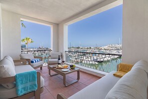 A balcony with a view of a marina, a sofa, a coffee table with food and drinks, and a chair. - Apartamento Vintage | 4 bedrooms | Vilamoura Marina (Vilamoura)