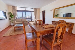 A living room with a wooden dining table, two sofas, a chessboard, and a large mirror. - Apartamento Vintage | 4 bedrooms | Vilamoura Marina (Vilamoura)