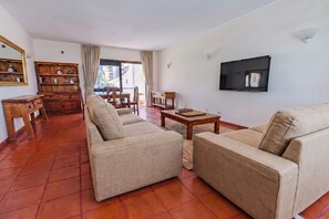 A living room with a sofa set, a wooden coffee table, a TV mounted on the wall, and a chessboard on the table. - Apartamento Vintage | 4 bedrooms | Vilamoura Marina (Vilamoura)