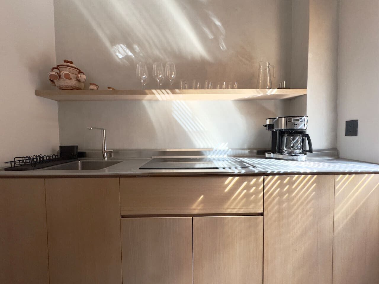 Ett modernt kök med en diskho i rostfritt stål, en kaffebryggare och en bänkskiva i trä.