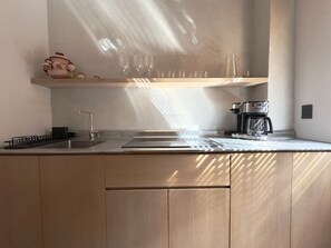 Eine moderne Küche mit Spüle aus Edelstahl, einer Kaffeemaschine und einer Holzarbeitsplatte.