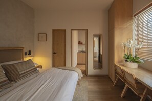 Une chambre à coucher avec un lit, une table de chevet, un miroir et une plante orchidée en pot.