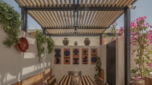 An outdoor patio with a wooden table and benches, surrounded by potted plants and decorative vases. - NEW Beautiful loft - KS bed - A/C Roma Norte (Ciudad de México)