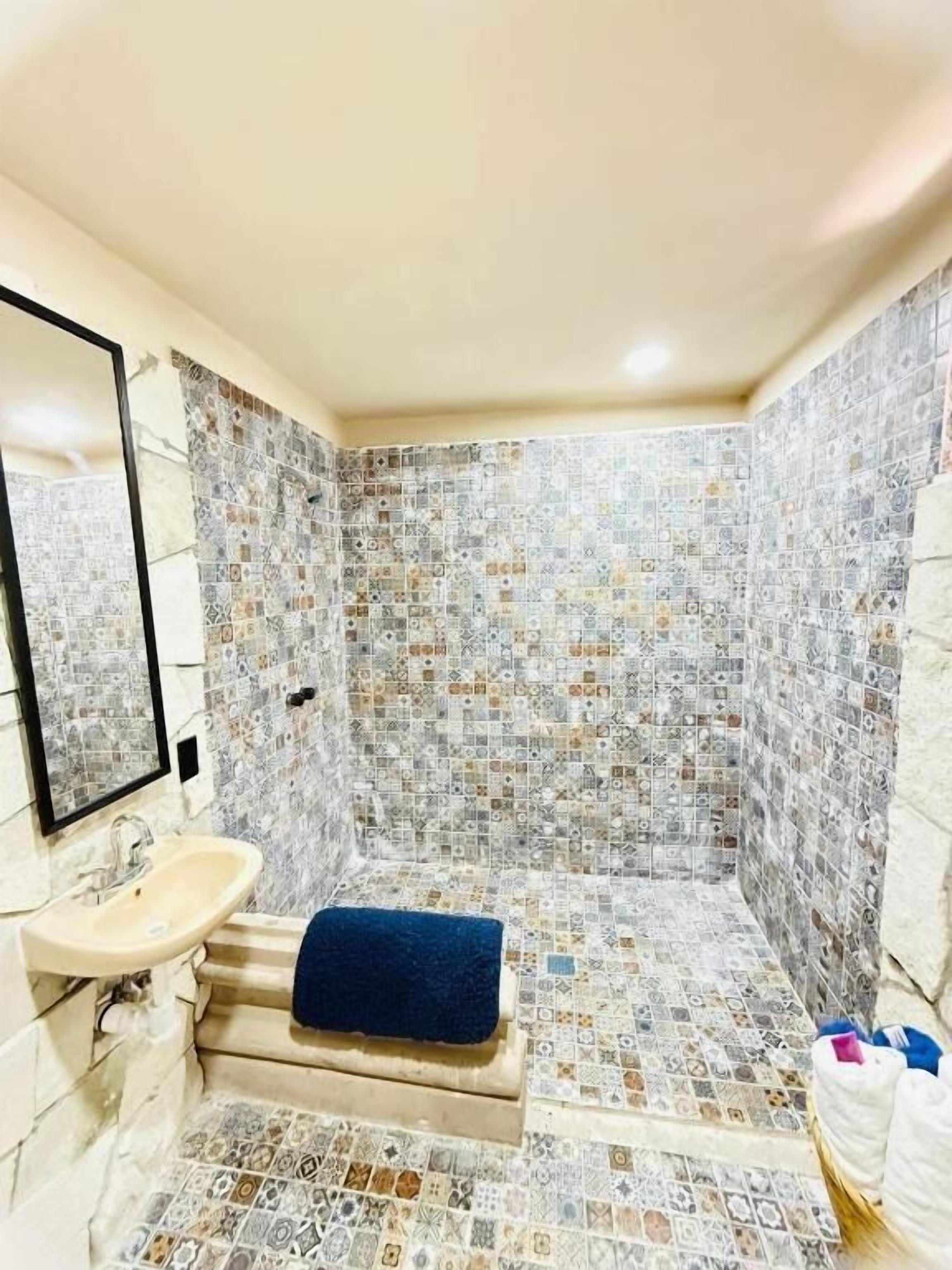 Um banheiro com piso de azulejos, pia, espelho e toalha.