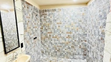 Um banheiro com piso de azulejos, pia, espelho e toalha.