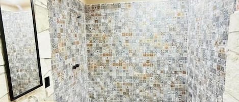 A bathroom with a tiled floor, a sink, a mirror, and a towel.