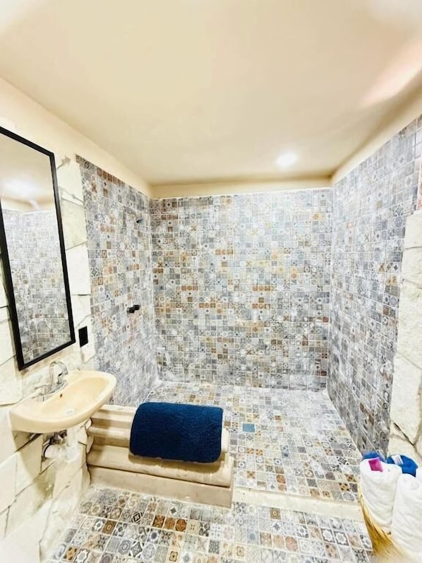 A bathroom with a tiled floor, a sink, a mirror, and a towel.