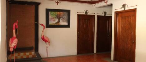 A hallway with a tiled floor, wooden doors, and a framed picture on the wall.