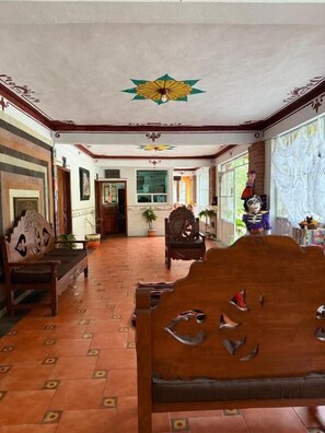 Una habitación con un banco de madera, piso estampado y techo decorativo.