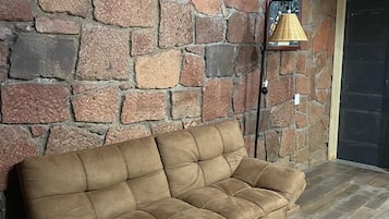 A brown sofa against a stone wall with a lamp and a door in the background.