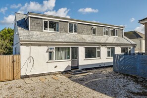 A two-story residential building with a sloped roof, multiple windows, and a gravel driveway. - 1 Bedroom Apartment Sleeps 2 - Pets Welcome (St Ives)