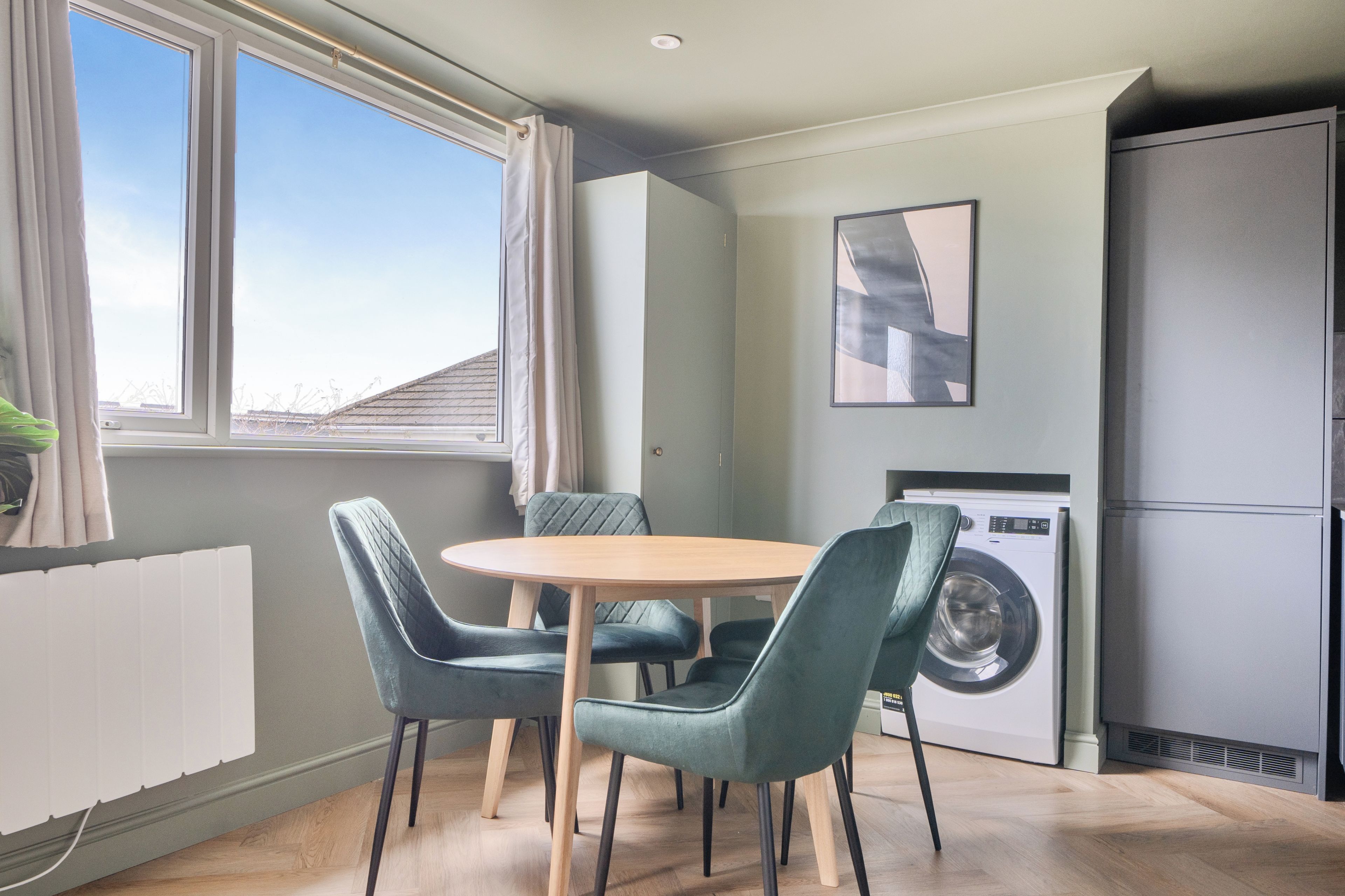 A compact kitchen with a dining area, a washing machine, and a refrigerator.