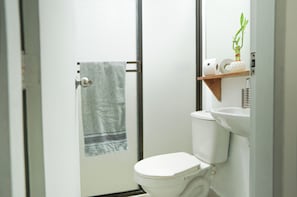 A bathroom with a toilet, a towel rack, a sink, and a shelf with a plant. - Heart of Laureles: Beautiful 2BR Near Best Cafes & Restaurants (Antioquia)