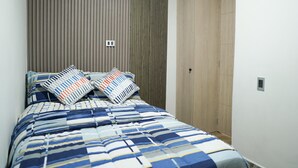 Un dormitorio con cama, dos almohadas, cabecera de madera y un armario.