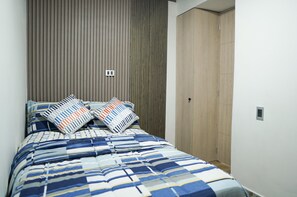 A bedroom with a bed, two pillows, a wooden headboard, and a wardrobe. - Heart of Laureles: Beautiful 2BR Near Best Cafes & Restaurants (Antioquia)