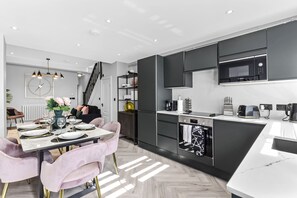 A modern kitchen with black cabinets, a microwave, and a coffee maker. - The Ultimate Hangout 4BR Modern House with Garden (Enfield)